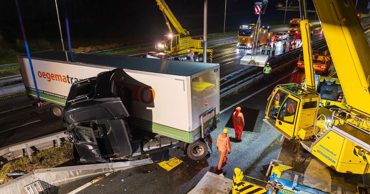In beeld: Vrachtwagen schaart op A28 en knalt door vangrail, chauffeur gewond