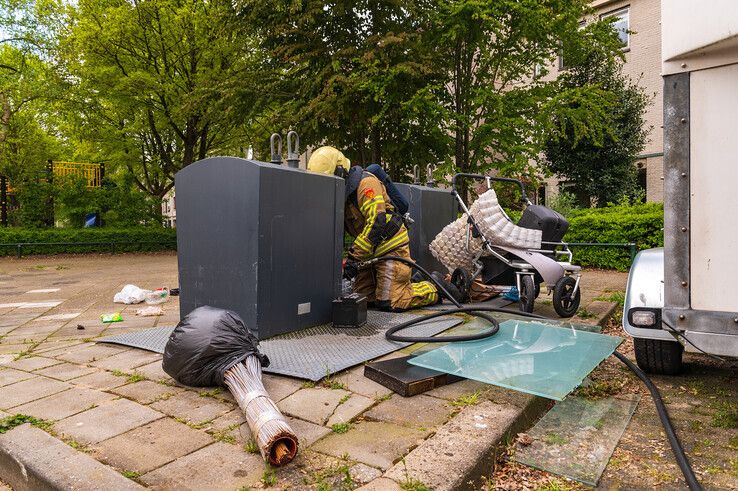 Brandweerlieden moesten zich een weg banen door het afval om een containerbrand te blussen aan de Van den Tyverbelt . - Foto: Peter Denekamp