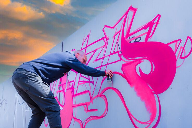 Late, een Zwolse graffitikunstenaar in actie bij de graffitimuur in Stadshagen. - Foto: Peter Denekamp