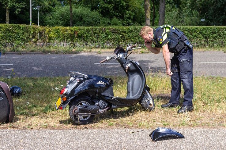 Een agent bekijkt de schade aan de scooter. - Foto: Ruben Meinten