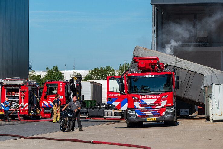 De brandweer trekt de brandende container weg bij het bedrijfspand. - Foto: Peter Denekamp