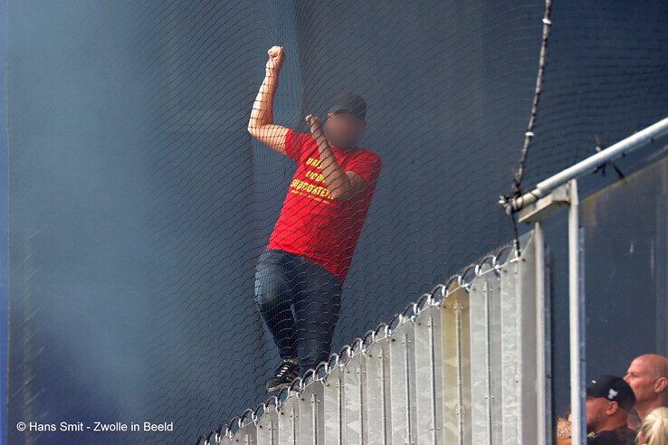 Een Go Ahead Eagles-fan klimt op een hek in het uitvak om aan de rook te ontsnappen. - Foto: Hans Smit