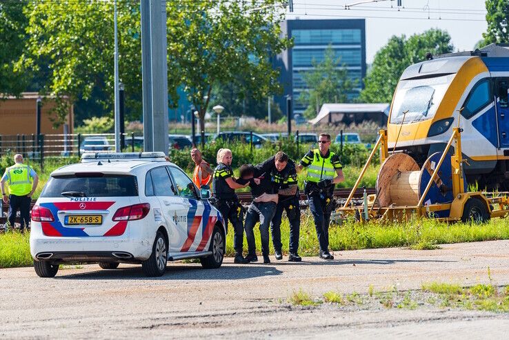 De politie haalt de verwarde man van het spoor nabij het station. - Foto: Peter Denekamp