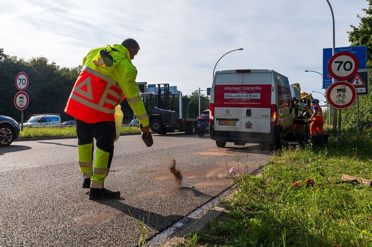 Een medewerker van Rova reinigt het door het ongeval vervuilde wegdek. - Foto: Peter Denekamp