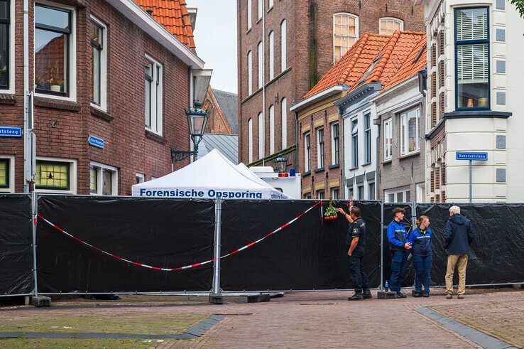 Bloemen voor de onbekende overledene in de Buiten Nieuwstraat terwijl het onderzoek nog volop bezig is. - Foto: Peter Denekamp