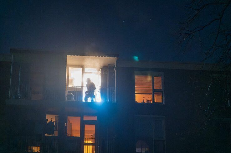 Een brandweerman zet de rokende pan op het balkon van het appartement. - Foto: Peter Denekamp