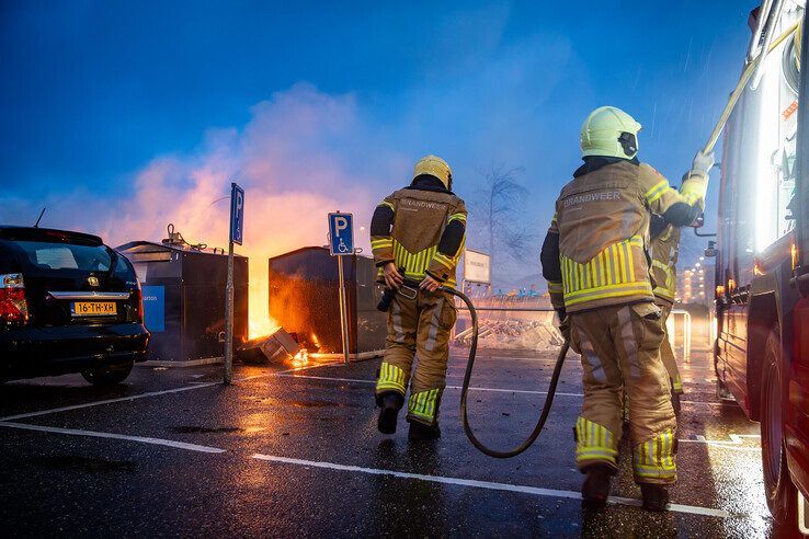 Brandweerlieden blussen op nieuwsjaarsochtend de brandende papiercontainers in Stadshagen. - Foto: Hugo Janssen