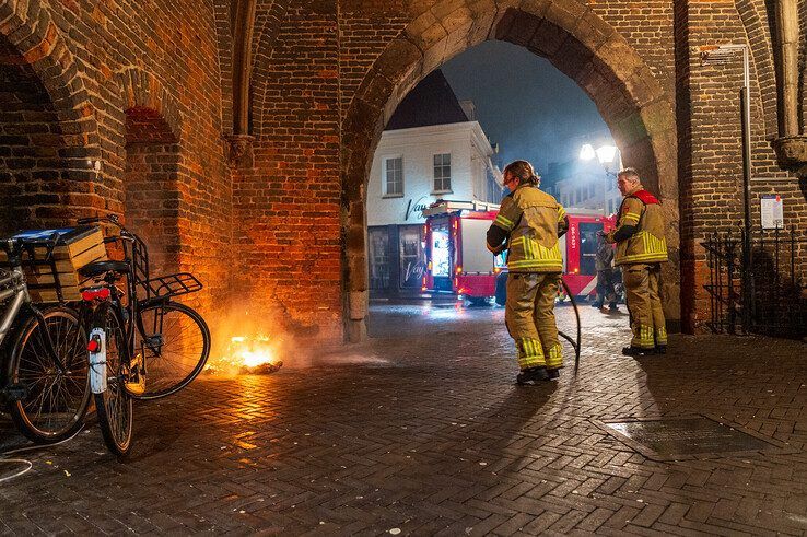 Een brandweervrouw blust het brandje onder de Sassenpoort. - Foto: Peter Denekamp