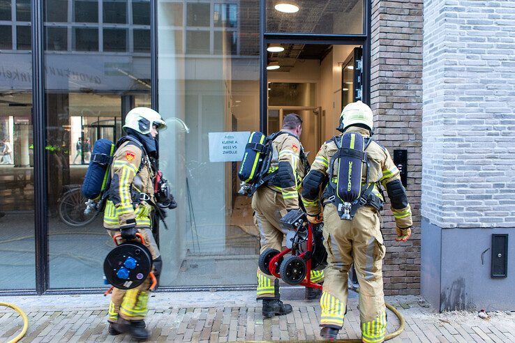 Brandweerlieden gaan het appartement ventileren om de rook te verdrijven. - Foto: Ruben Meinten