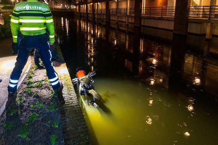 De jongeman ging met zijn bromfiets kopje onder in het water langs de Koggelaan. - Foto: Peter Denekamp