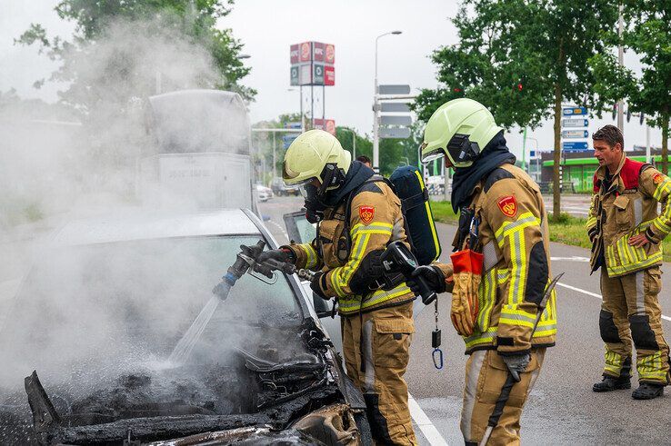 Brandweerlieden blussen de autobrand op de Meppelerstraatweg. - Foto: Peter Denekamp