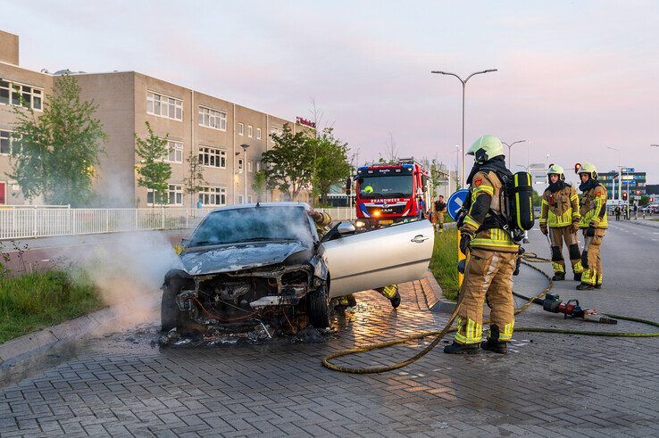 Brandweerlieden blussen de autobrand op de Russenweg. - Foto: Peter Denekamp