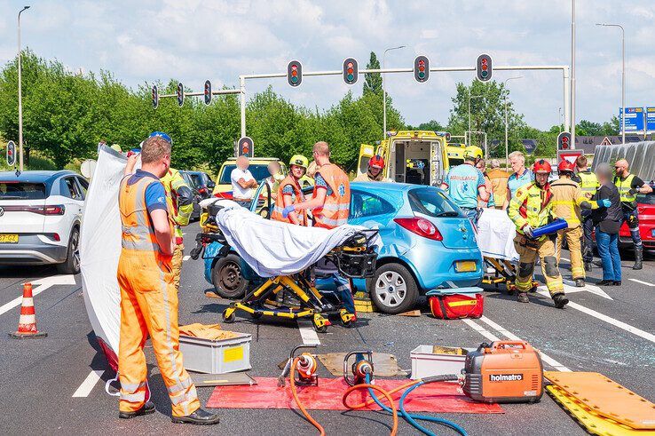 Hulpverleners zijn bezig het oudere echtpaar uit de auto te halen. - Foto: Peter Denekamp