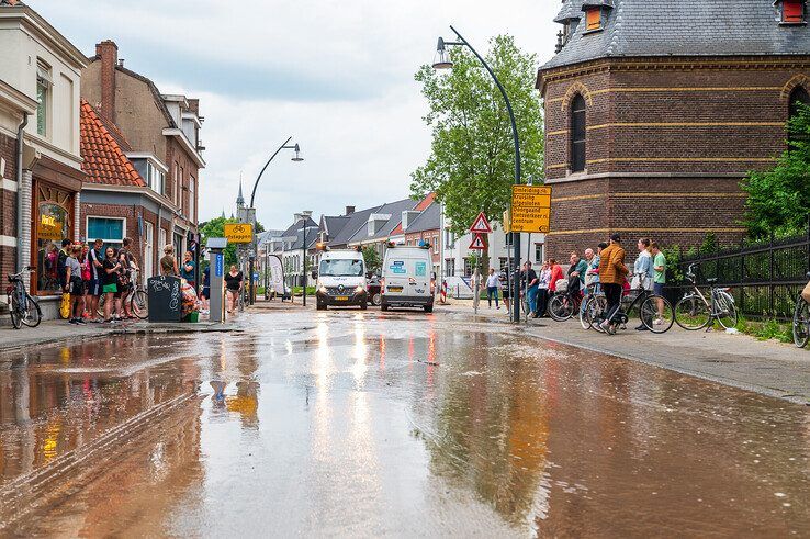 De Assendorpstraat is bedekt met een dikke laag modder. - Foto: Peter Denekamp