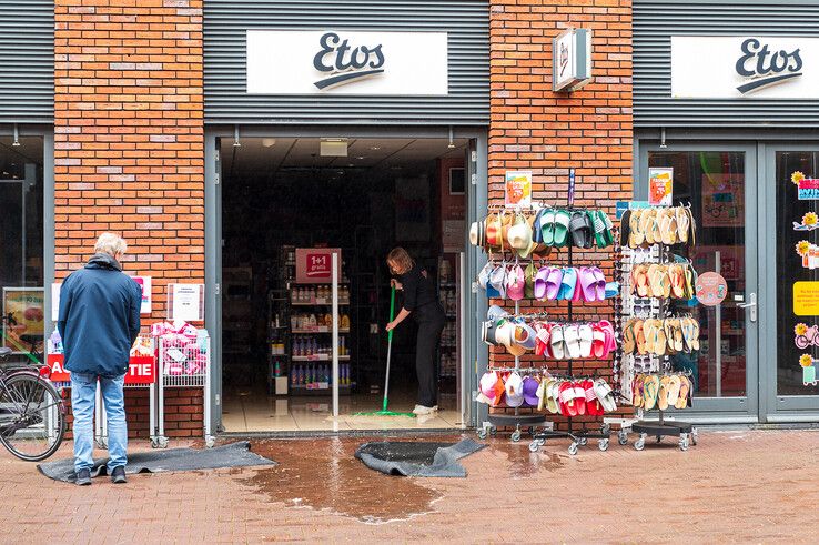 Een medewerkster van Etos in de weer met een trekker om het water uit de winkel te krijgen.  - Foto: Peter Denekamp