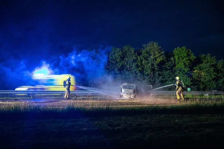 Brandweerlieden blussen de auto op de snelweg. - Foto: Hugo Janssen
