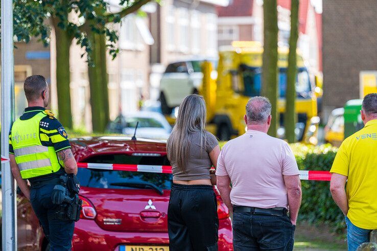 Buurtbewoners bij het afzetlint terwijl de in beslag genomen auto wordt afgevoerd. - Foto: Peter Denekamp