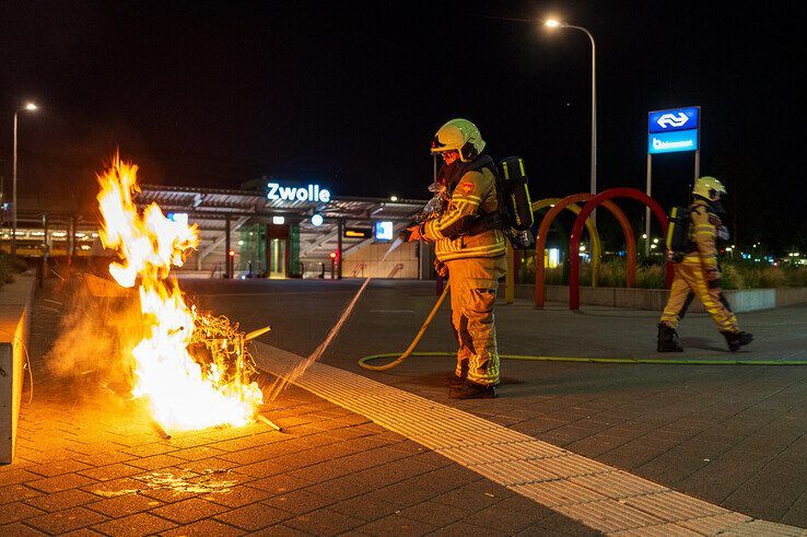 Een brandweerman blust de brandende terrasstoelen achter het station. - Foto: Peter Denekamp