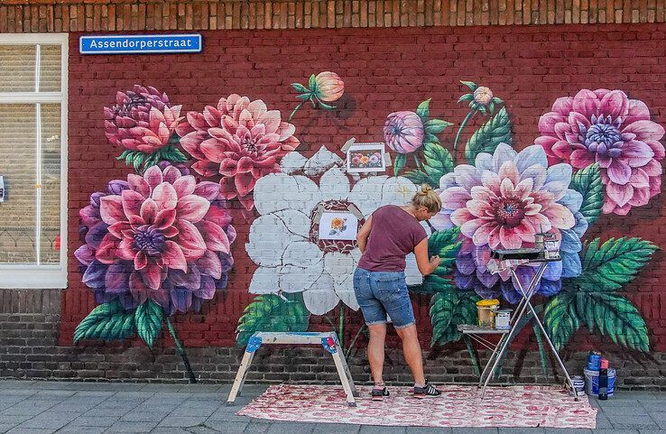 Lonneke schildert grote dahlia's op de muur. - Foto: Obbe Bakker