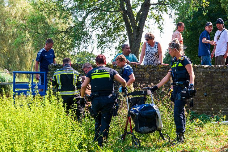 Brandweerlieden helpen de man uit de Wavin-vijver. - Foto: Peter Denekamp