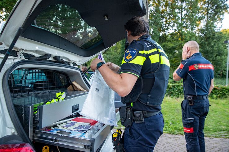 Politieagenten doorzoeken een auto bij de zorgwoningen. - Foto: Hugo Janssen