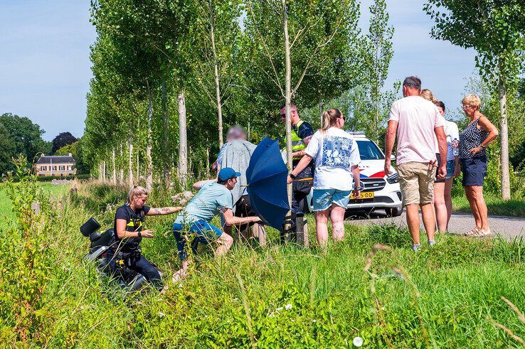 Omstanders en politieagenten helpen de man uit de sloot. - Foto: Peter Denekamp