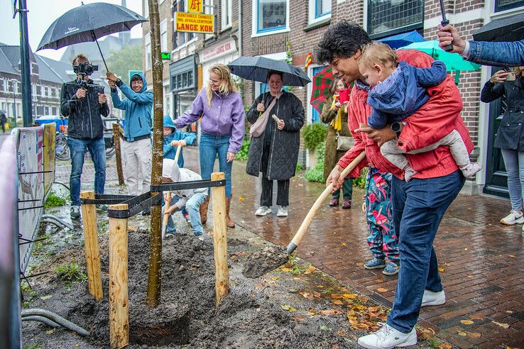 Bewoners trotseren de regen om de eerste nieuwe boom te planten. - Foto: Obbe Bakker