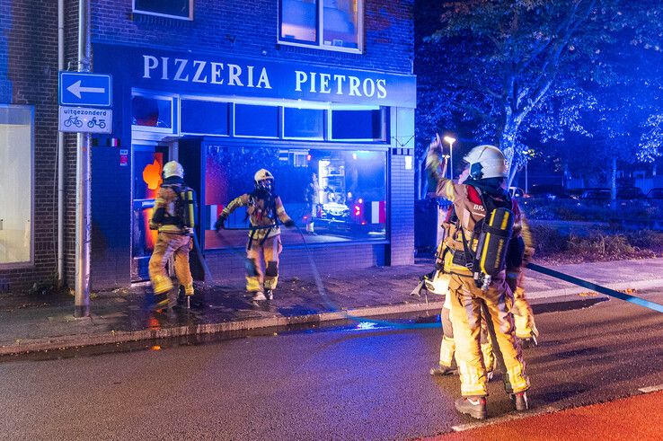 Brandweerlieden bij de brandende pizzeria aan de Assendorperstraat. - Foto: Peter Denekamp