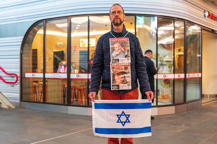 Zwijgzaam staat dominee Marten Visser met de Israëlische vlag in de reizigerstunnel tijdens het pro-Palestijnse protest. - Foto: Peter Denekamp