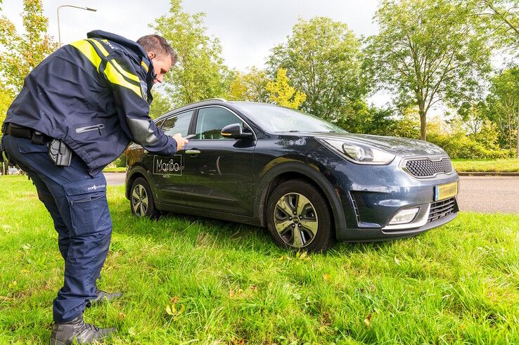 Een agent fotografeert de schade aan de auto op de Middelweg. - Foto: Peter Denekamp