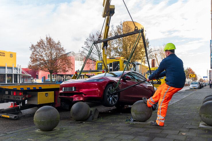 In beeld: Achterwaarts inparkeren op Hanzelaan gaat fout, Tesla muurvast op betonnen bol - Foto: Peter Denekamp