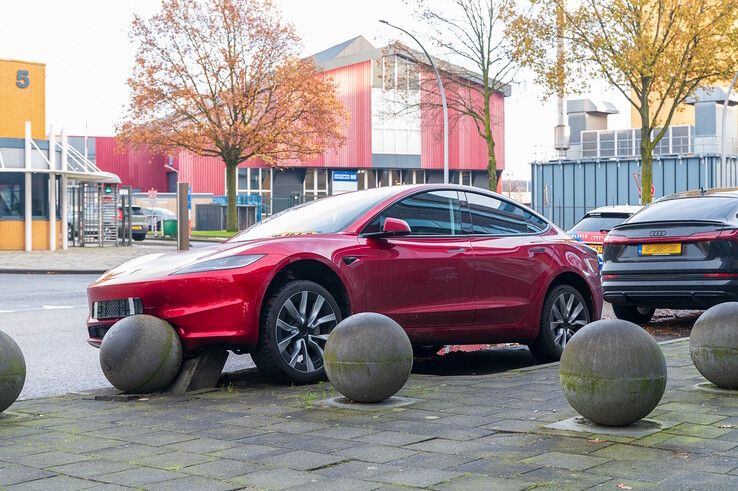 In beeld: Achterwaarts inparkeren op Hanzelaan gaat fout, Tesla muurvast op betonnen bol - Foto: Peter Denekamp