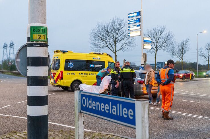 Ambulancepersoneel helpt de automobilist uit zijn auto. - Foto: Peter Denekamp