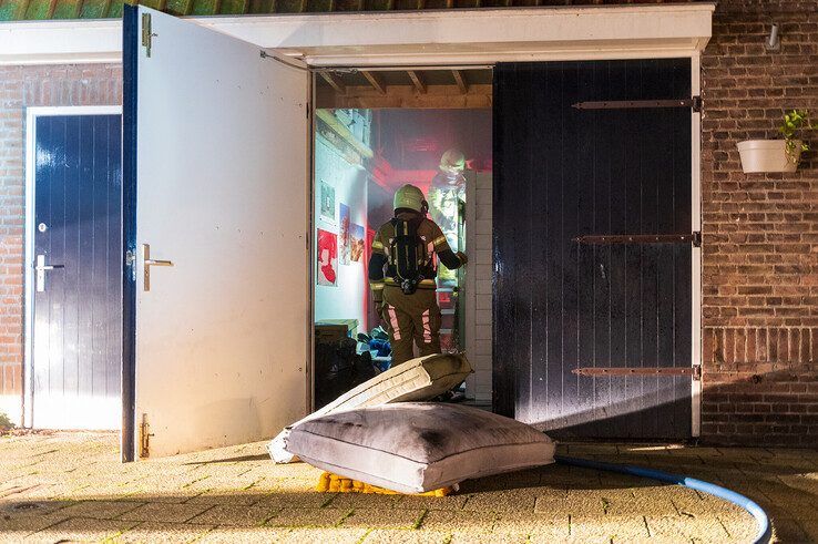 Brandweerlieden blussen de brand in de schuur. - Foto: Peter Denekamp