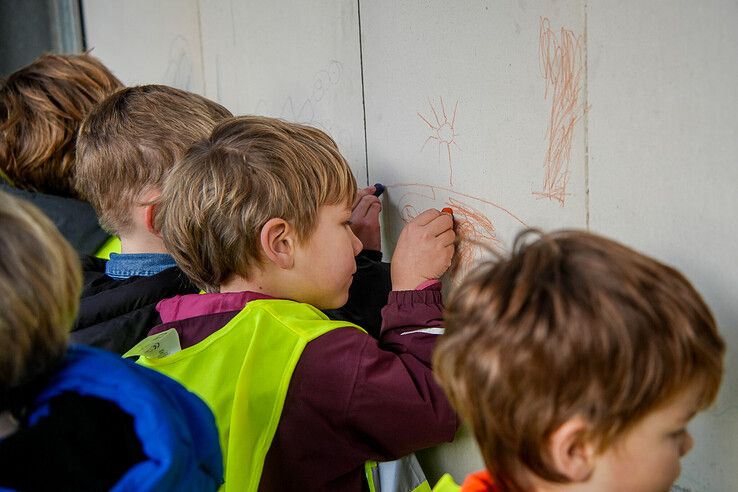 Schoolkinderen schrijven hun namen op de muur. - Foto: Obbe Bakker