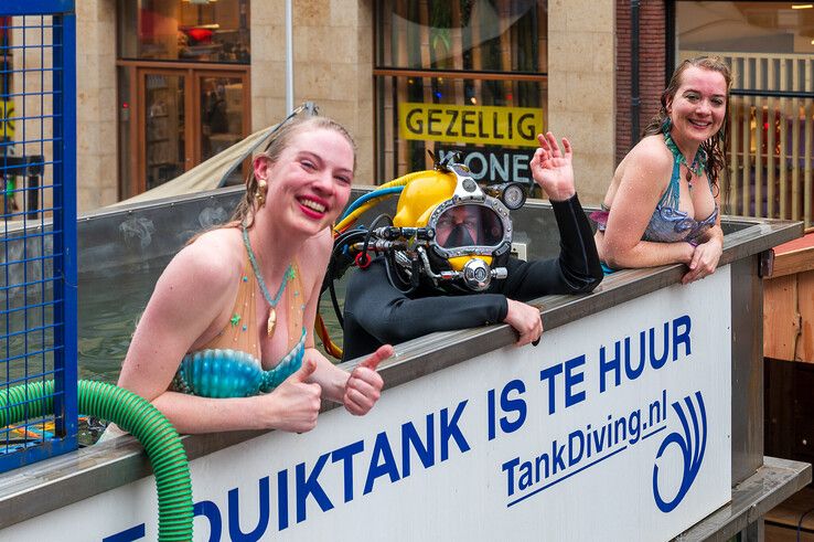 Patrick Bakker met duikhelm en twee zeemeerminnen in het Glazen Onderwaterhuis. - Foto: Peter Denekamp