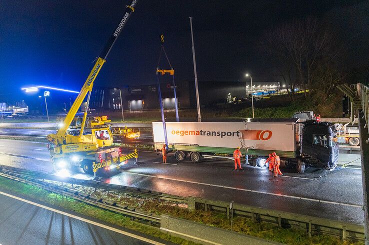 In beeld: Vrachtwagen schaart op A28 en knalt door vangrail, chauffeur gewond - Foto: Peter Denekamp