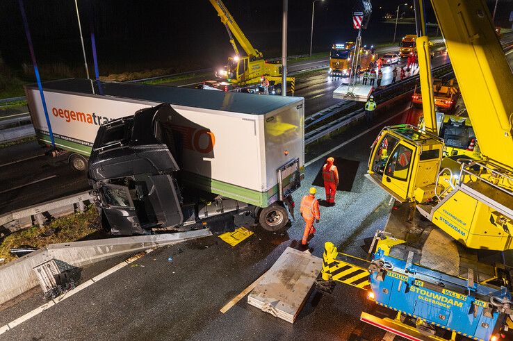 In beeld: Vrachtwagen schaart op A28 en knalt door vangrail, chauffeur gewond - Foto: Peter Denekamp