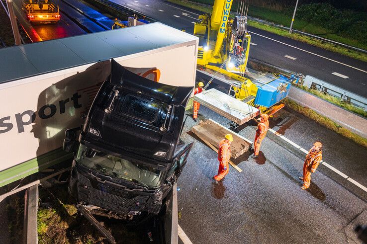 In beeld: Vrachtwagen schaart op A28 en knalt door vangrail, chauffeur gewond - Foto: Peter Denekamp