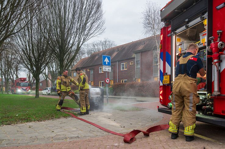 Brandweerlieden blussen de brand in de ondergrondse container. - Foto: Peter Denekamp