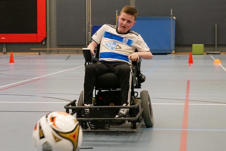 Een elektrische rolstoelvoetballer scoort in de sporthal van Vogellanden. - Foto: Vogellanden