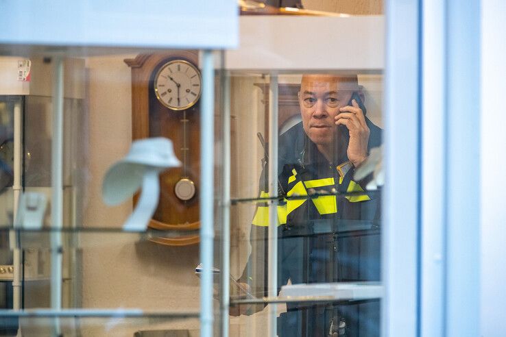 Een politieman in de overvallen klokkenmakerij. - Foto: Hugo Janssen