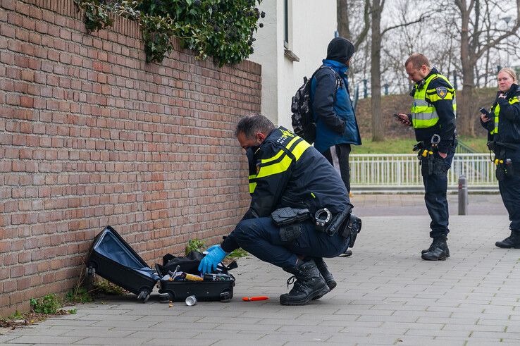 Een agent doorzoekt de koffer op de Oosterlaan. - Foto: Peter Denekamp