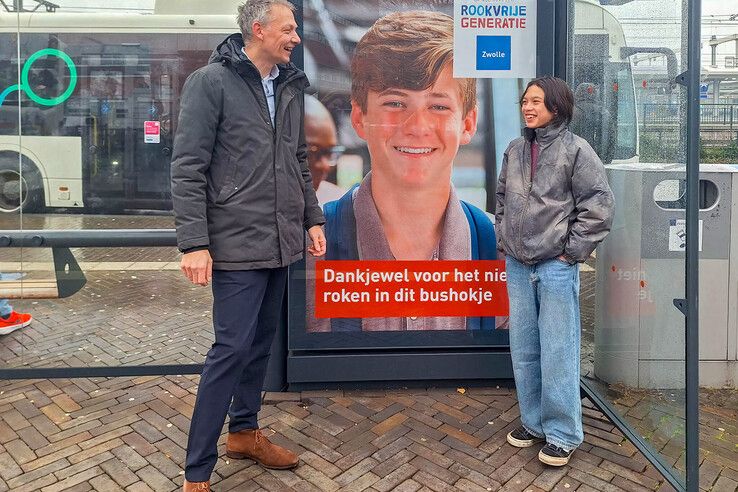 Wethouder Michiel van Willigen en kinderburgemeester Daniël in een bushokje met de nieuwe poster. - Foto: Gemeente Zwolle