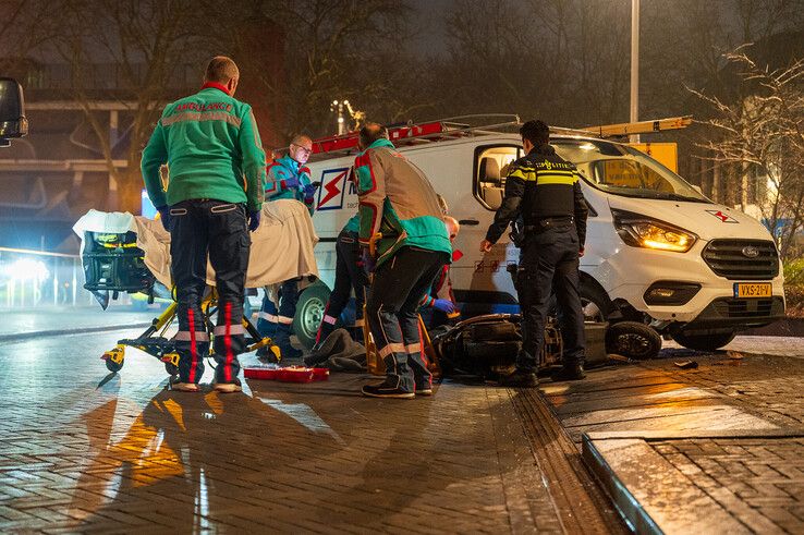 Ambulancepersoneel behandelt de gewonde scooterrijder op het Stationsplein. - Foto: Peter Denekamp