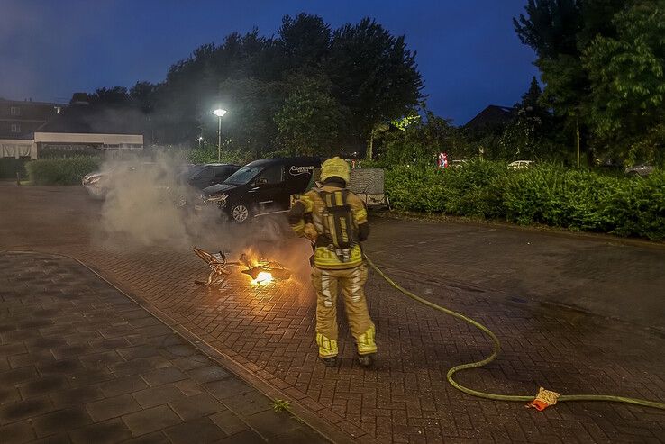 Een brandweerman blust de Spartamet op de Jacob Catsstraat.
