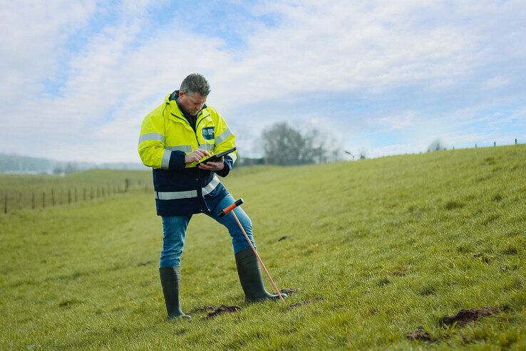 Een dijkbeheerder inspecteert de dijk.
