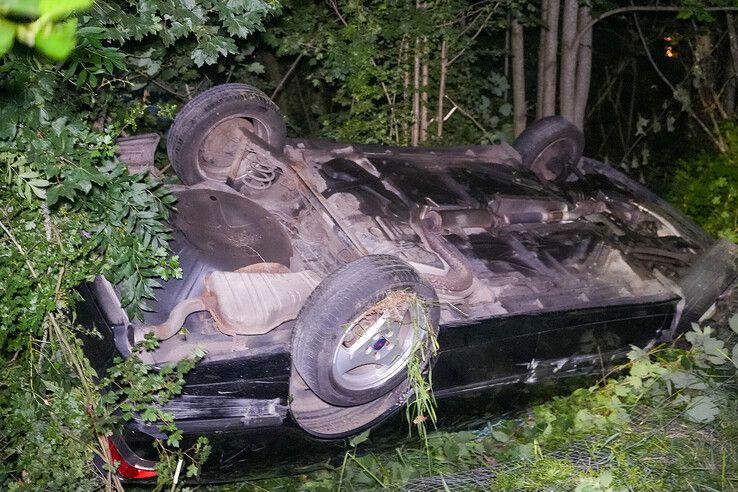 Auto ligt op de kop onderaan de dijk in Kampen.