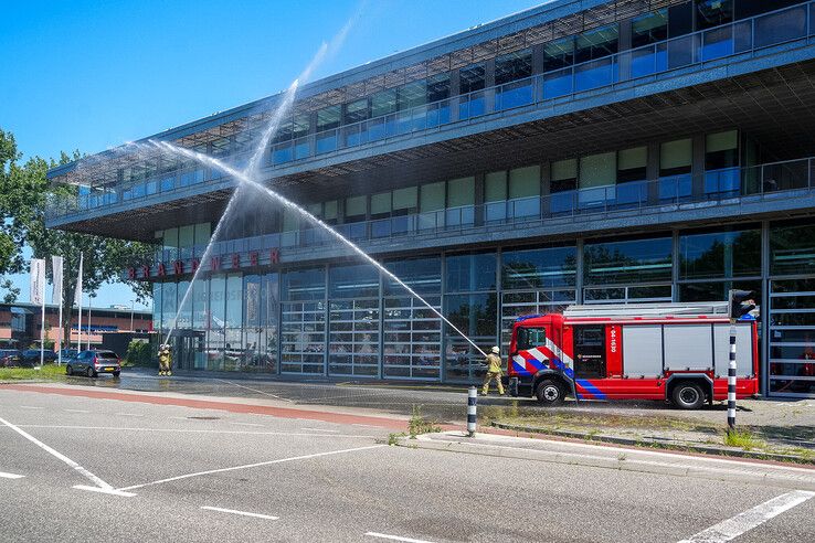 Brandweerlieden in Zwolle vormen een waterboog bij de kazerne aan de Marsweg.