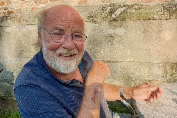 Henk Mussche genietend van een glas wijn op het terras in het zonnetje.